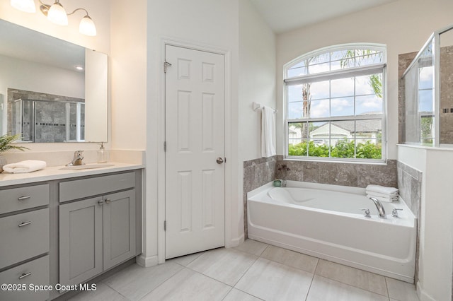 bathroom with tile patterned flooring, a garden tub, vanity, and a healthy amount of sunlight