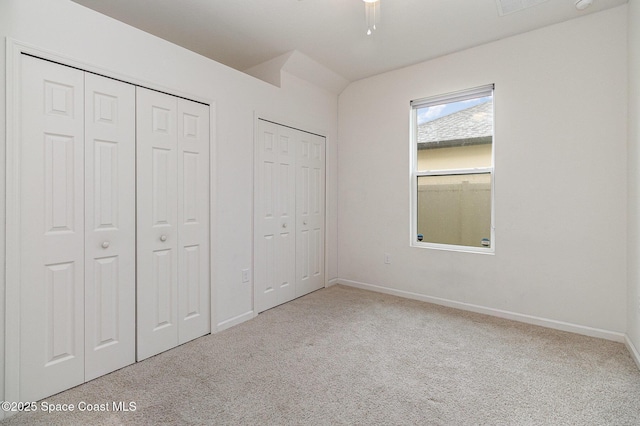 unfurnished bedroom featuring baseboards, two closets, and carpet flooring