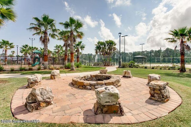 view of home's community featuring a patio, a fire pit, playground community, fence, and a yard