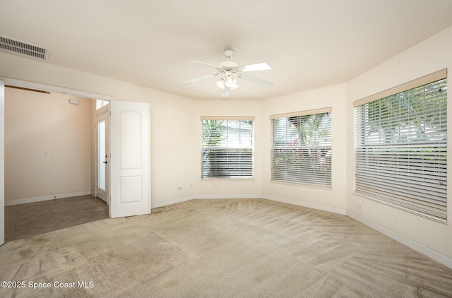 carpeted empty room with baseboards, visible vents, and a ceiling fan