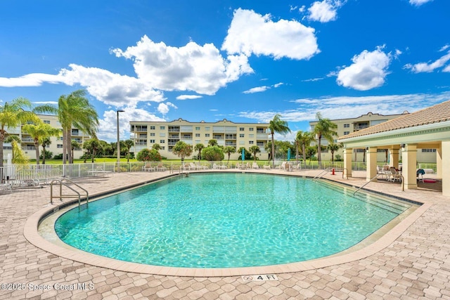 community pool with a patio area and fence