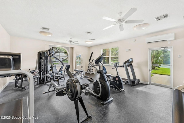 gym featuring visible vents, a textured ceiling, baseboards, and a wall mounted AC