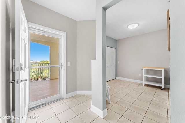 doorway with light tile patterned floors and baseboards