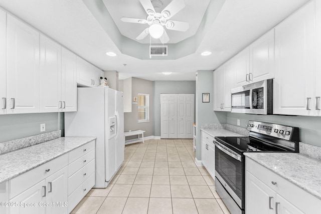 kitchen featuring light tile patterned floors, visible vents, a tray ceiling, stainless steel appliances, and white cabinetry