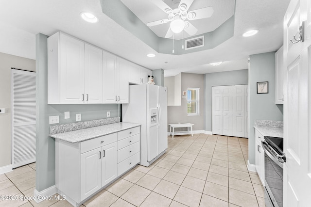 kitchen featuring light tile patterned floors, white refrigerator with ice dispenser, visible vents, a raised ceiling, and electric stove