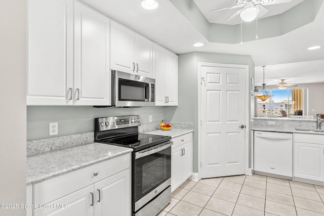 kitchen with ceiling fan, a sink, white cabinets, appliances with stainless steel finishes, and a tray ceiling