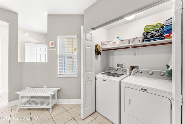 laundry area featuring washing machine and dryer, laundry area, baseboards, and light tile patterned floors