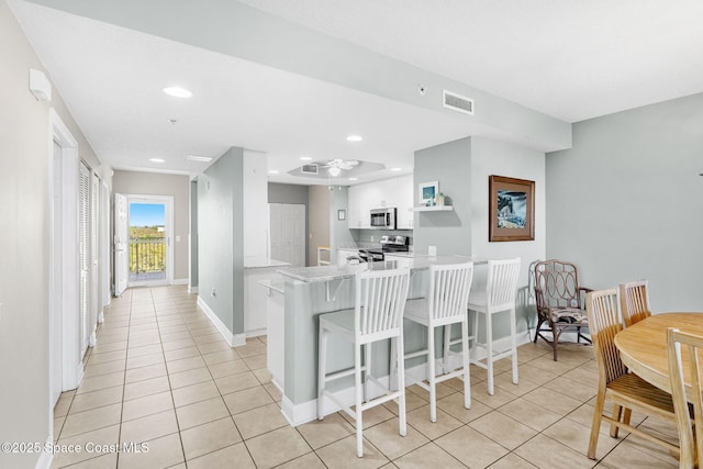 kitchen with stainless steel appliances, a peninsula, visible vents, white cabinetry, and light countertops