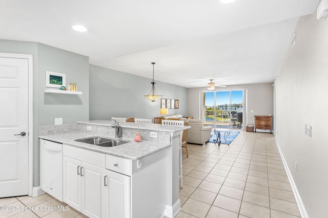 kitchen featuring light tile patterned floors, open floor plan, a sink, dishwasher, and a peninsula