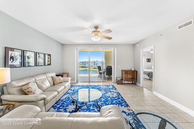 living area with light tile patterned floors, baseboards, visible vents, a ceiling fan, and a textured ceiling