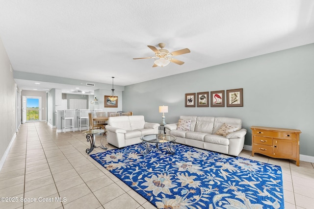 living room with light tile patterned floors, visible vents, ceiling fan, a textured ceiling, and baseboards