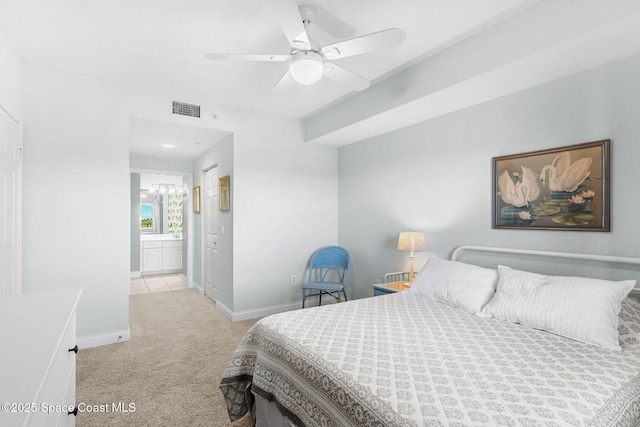 bedroom with baseboards, visible vents, light colored carpet, ensuite bath, and ceiling fan