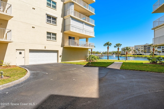 view of building exterior with a water view, driveway, and a garage