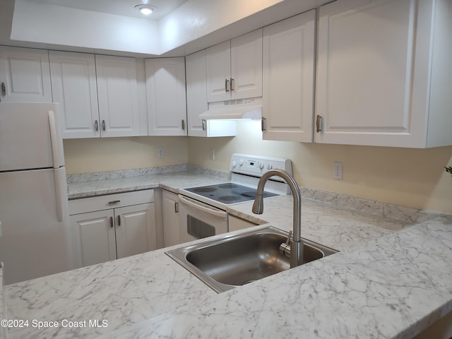 kitchen featuring under cabinet range hood, white appliances, a sink, white cabinets, and light countertops