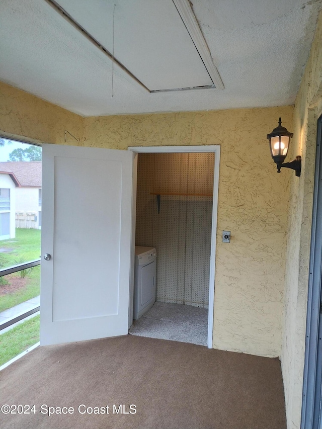 interior space featuring attic access, washer / clothes dryer, and a textured wall