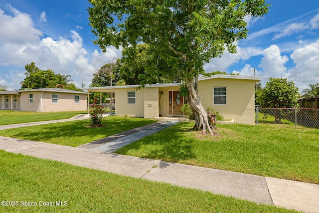 view of front facade with an attached carport, fence, concrete driveway, stucco siding, and a front lawn