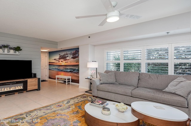 living area featuring a ceiling fan, light tile patterned flooring, and wood walls