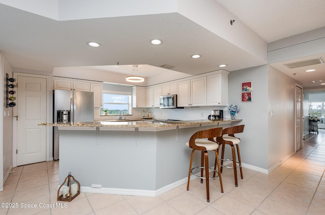 kitchen with visible vents, appliances with stainless steel finishes, a peninsula, white cabinetry, and recessed lighting