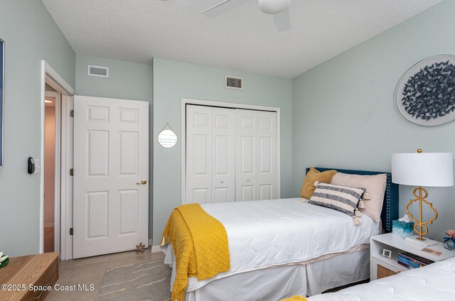 tiled bedroom with a textured ceiling, ceiling fan, a closet, and visible vents