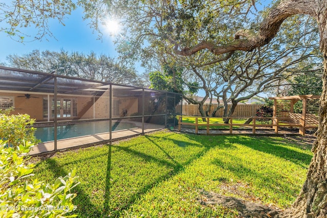 view of yard featuring a lanai, ceiling fan, fence, and a fenced in pool