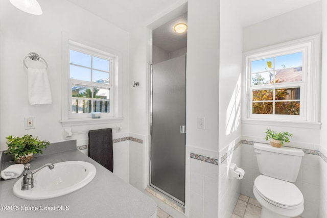 bathroom with toilet, a shower stall, tile walls, and a sink