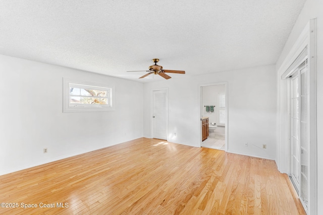 interior space featuring light wood-style floors, a textured ceiling, and ensuite bath