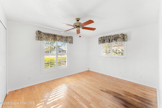 spare room with ceiling fan, a textured ceiling, baseboards, and wood finished floors