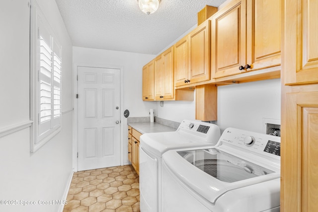 washroom featuring cabinet space, a textured ceiling, and washing machine and clothes dryer