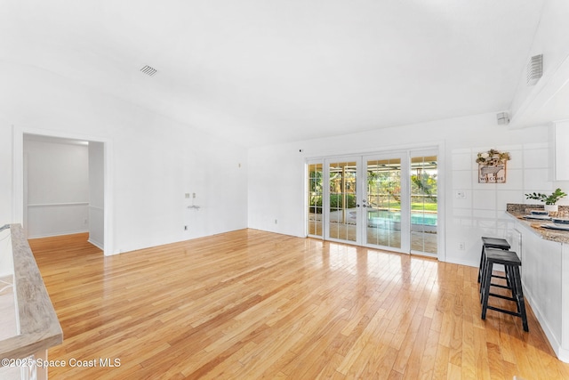 unfurnished living room featuring light wood finished floors, visible vents, and french doors