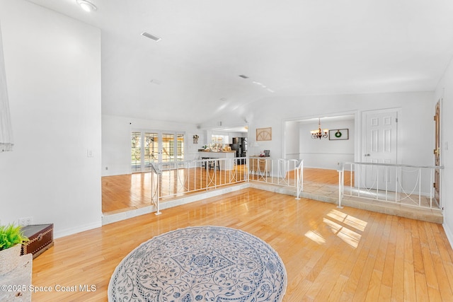 interior space with lofted ceiling, visible vents, an inviting chandelier, wood finished floors, and baseboards