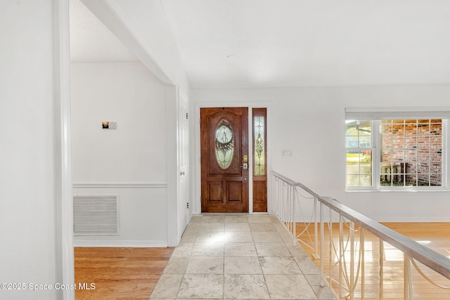 foyer with light wood-type flooring, baseboards, and visible vents