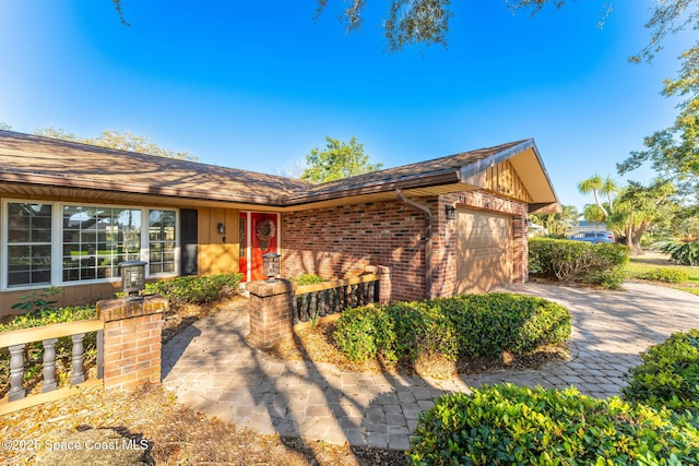 view of front of home with an attached garage, decorative driveway, and brick siding