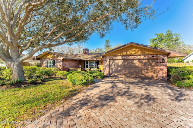 ranch-style home featuring a garage, decorative driveway, brick siding, and a chimney