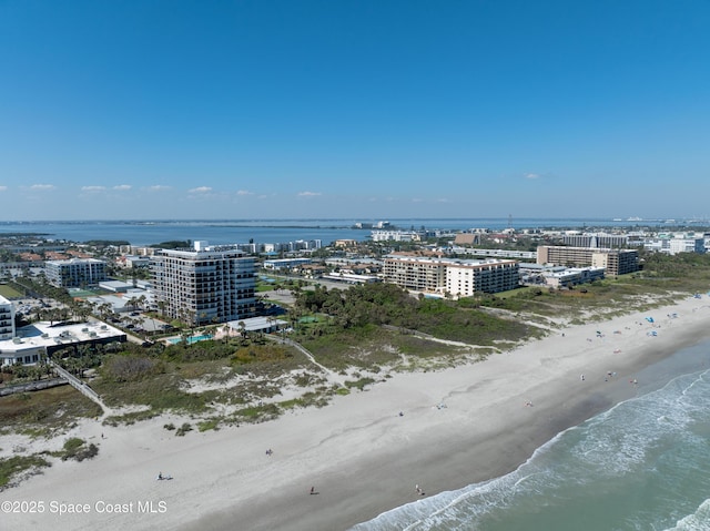 drone / aerial view featuring a water view, a beach view, and a city view