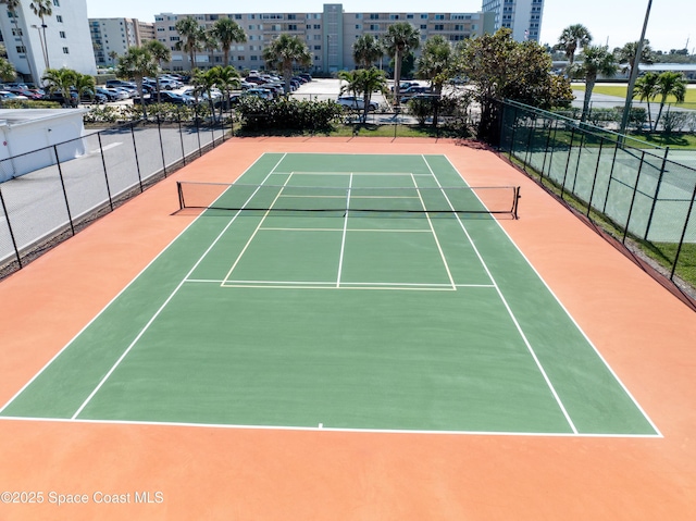 view of tennis court featuring community basketball court, a view of city, and fence