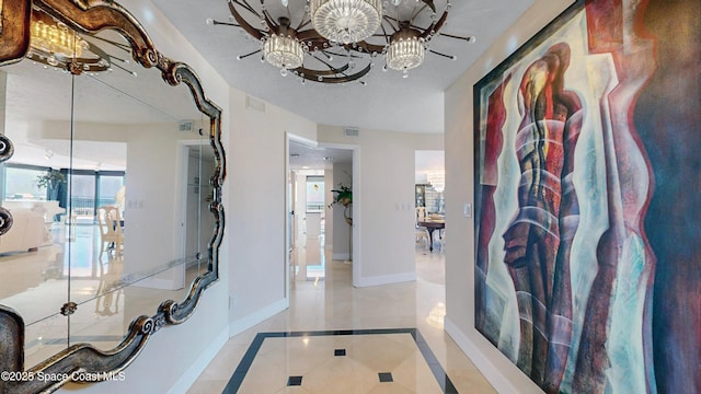 corridor with visible vents, baseboards, and a notable chandelier