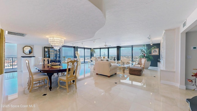 dining area featuring visible vents, rail lighting, expansive windows, a textured ceiling, and baseboards