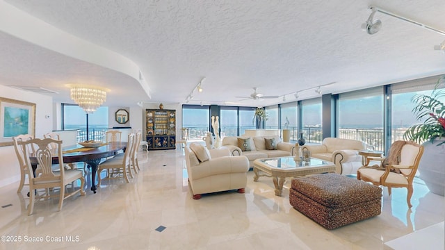 living area featuring a chandelier, expansive windows, rail lighting, and a textured ceiling