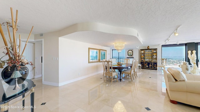 dining room featuring visible vents, an inviting chandelier, a textured ceiling, track lighting, and baseboards