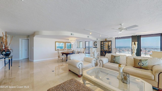 living area with a healthy amount of sunlight, baseboards, a textured ceiling, and ceiling fan with notable chandelier