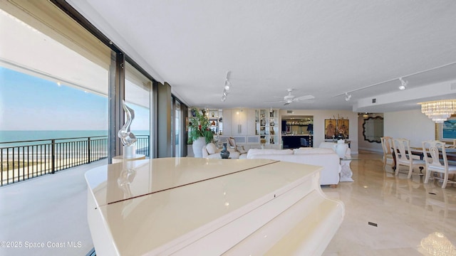 kitchen featuring ceiling fan with notable chandelier, a water view, and track lighting