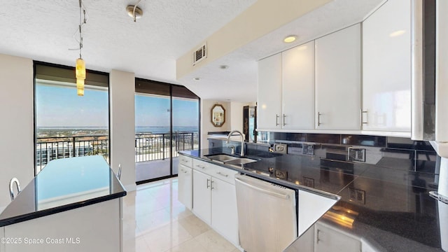 kitchen featuring tasteful backsplash, dark countertops, white cabinets, a sink, and dishwasher