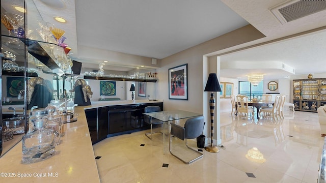 interior space with visible vents, a chandelier, and dark cabinets