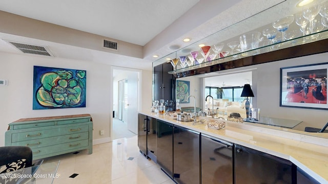 bar featuring indoor wet bar, visible vents, baseboards, and light tile patterned floors