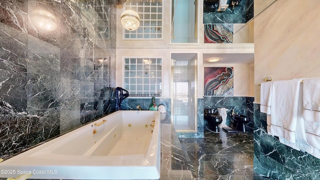 full bathroom featuring marble finish floor, tile walls, and a tub with jets