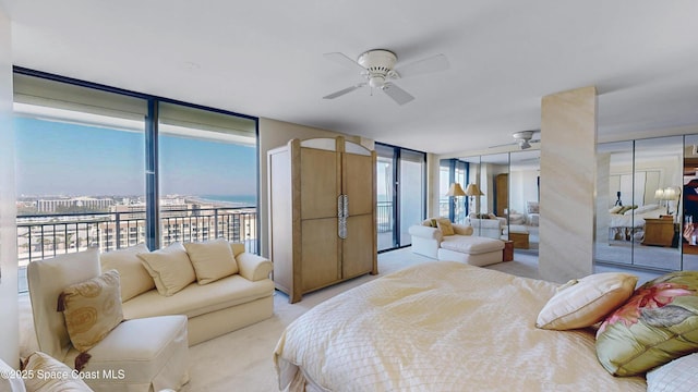 carpeted bedroom featuring ceiling fan, access to outside, and a wall of windows