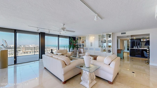 living room with a textured ceiling, a ceiling fan, visible vents, and floor to ceiling windows