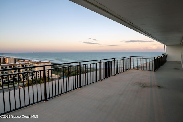 balcony at dusk featuring a water view