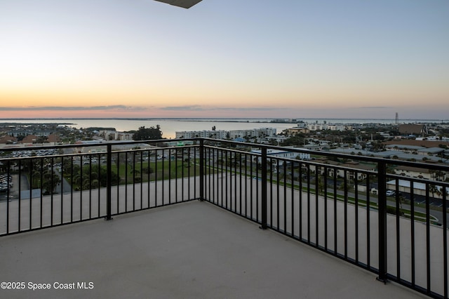 balcony at dusk featuring a water view