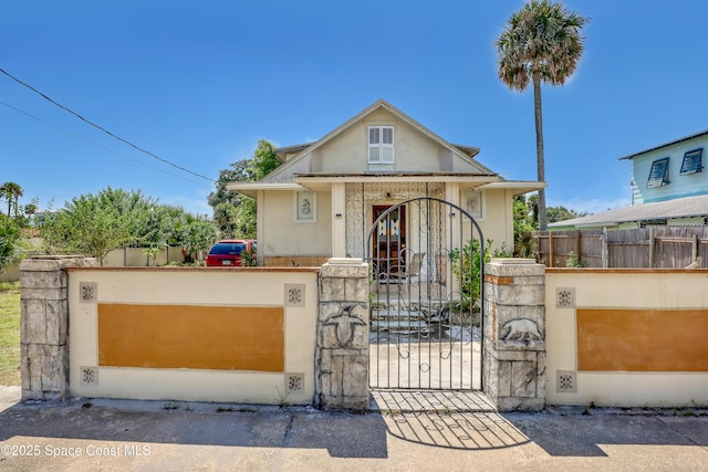 view of front of house featuring a fenced front yard, a gate, and stucco siding